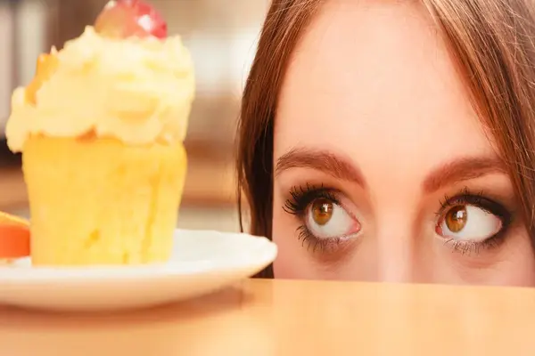 Woman peeking at a cupcake, suggesting strong sugar cravings