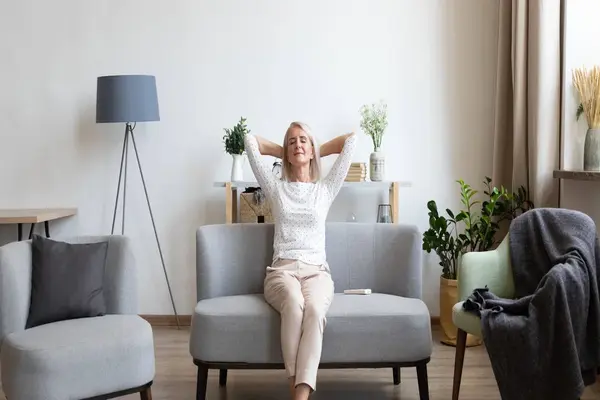 Woman relaxing on a sofa in a bright living room, suggesting a clean, comfortable home environment