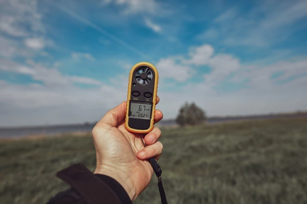 Hand holding a weather meter outdoors—humidity and wind changes can trigger eczema flares