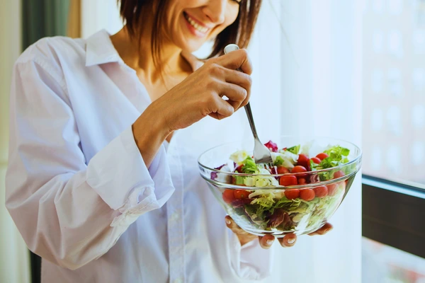 Woman eating a healthy salad—healthy eating alone may not fix stubborn weight