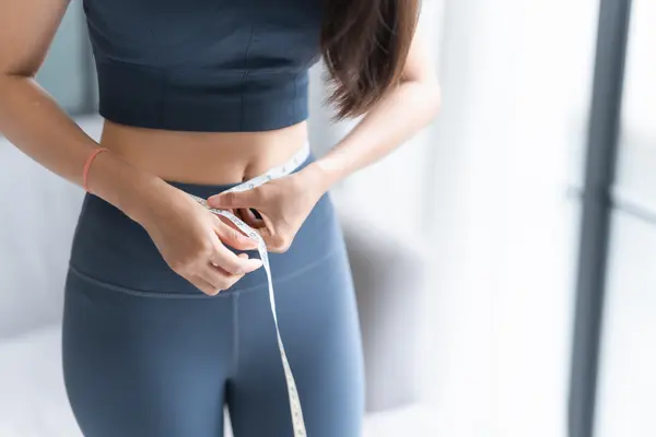 Woman measuring waist—bloating and stubborn weight can be linked to gut imbalance